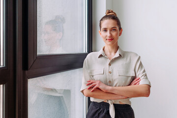 Wall Mural - Young businesswoman standing near window in the office