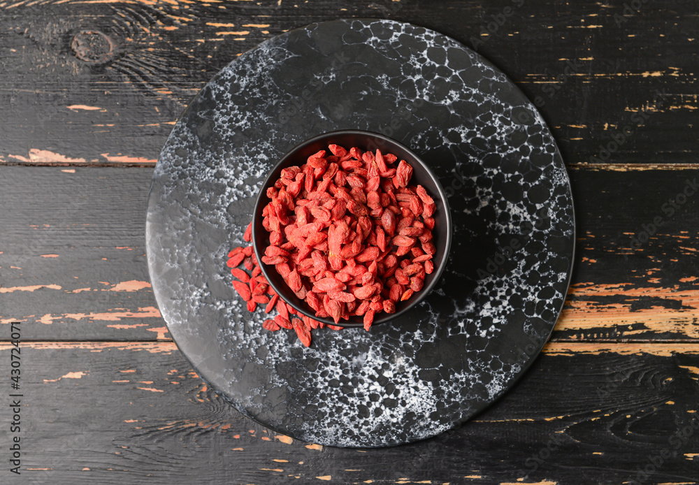 Bowl with dried goji berries on dark wooden background