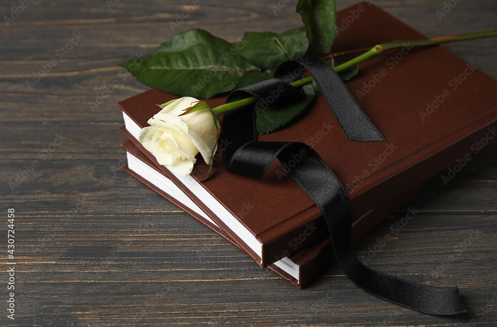 Rose with ribbon and books on dark wooden table