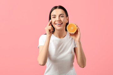 Wall Mural - Beautiful woman with orange applying facial cream on color background