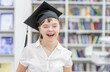 © Ermolaev Alexandr - Portrait of a happy girl with Down Syndrome wearing a graduation cap at a library