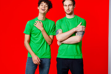 two men in green t-shirts are standing next to friendship red background