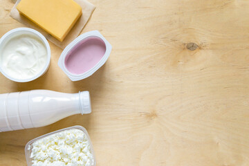 Wall Mural - Flat lay of dairy products. Milk, curd, sour cream, cheese and yogurt on wooden background, copyspace