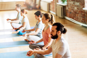 fitness, yoga and healthy lifestyle concept - group of people meditating in lotus pose at studio