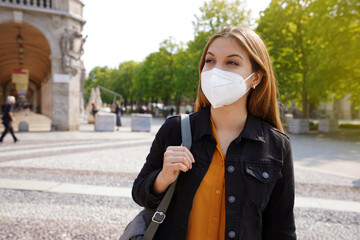 Wall Mural - Caucasian young woman wearing face mask FFP2 KN95 walking in city street