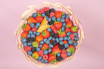 Wall Mural - Edible bouquet of fresh berries, blueberries, raspberries, strawberries, hedgehog on a pink background. View from the top .Close-up .Concept of a useful gift, congratulations on the holiday.