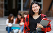 © Bangkok Click Studio - Young and cute Asian college student girls holding books, pose to camera with group of friends blur in background in front of school building. Learning and friendship of teens close friend concept