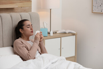 Canvas Print - Sick young woman with napkins and nasal spray in bed at home