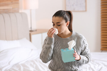 Canvas Print - Ill woman with box of paper tissues on bed at home