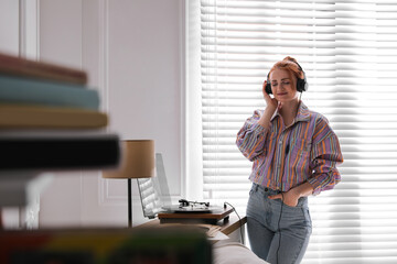 Wall Mural - Young woman listening to music with turntable at home