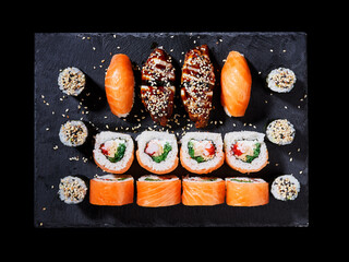 Wall Mural - Top view of sushi set with rolls of California, sashimi and maki on a black plate.