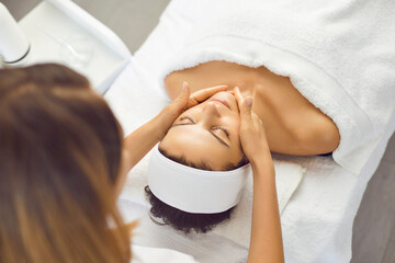 Wall Mural - Young beautiful woman has relaxed and is enjoying a facial massage from a spa specialist.