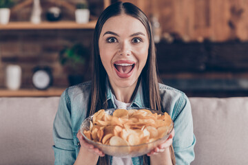 Sticker - Photo of cheerful excited young woman hold hands plate snacks potato chips eat food indoors inside house