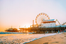 Santa Monica Pier On The Background Of An Orange Sunset, Calm Ocean Waves, Los Angeles, California