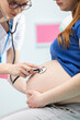 © fotodrobik - The doctor listens to the abdomen of a pregnant patient with a stethoscope. Professional medical office