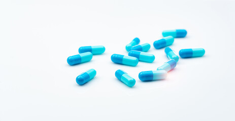 Sticker - Blue antibiotic capsule pills spread on white background. Antibiotic drug resistance. Pharmaceutical industry. Healthcare and medicine concept. Health budget concept. Capsule manufacturing industry.