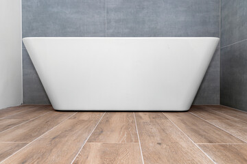 Wall Mural - A modern, free-standing wall-mounted bathtub, without a tap, standing in a bathroom lined with ceramic tiles.