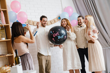Wall Mural - Excited couple blowing up surprise balloon during gender reveal party