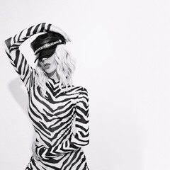 Sensual sexy androgenic model in freak stylish zebra print clothes and leather trendy black cap posing in a white studio. Clubbing party style