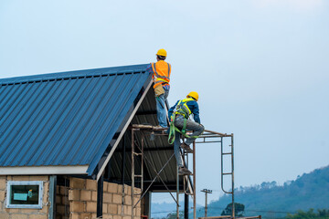 Poster - Construction worker using nail gun to install new roof on top roof,Residential building under construction concept.