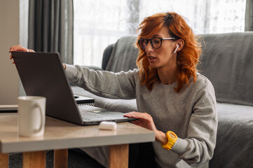 Woman using airpods and working on a laptop at home