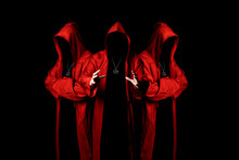 Mystery Three Sectarians In A Red Hooded Cloaks In The Dark. Unrecognizable Person. Hiding Face In Shadow. Conspiracy Concept.
