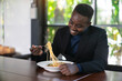 © arrowsmith2 - African businessman having a happy lunch with eating Spaghetti in restaurant
