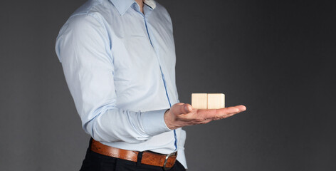 A businessman in a shirt holds two wooden cubes in his hand. Empty. Office. Workplace. Office worker.