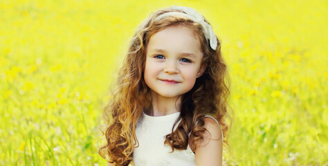 Wall Mural - Portrait of little girl child in spring field with dandelions flowers