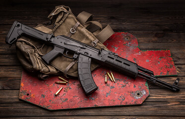 Canvas Print - A classic Soviet military rifle AK in a modern body kit. The carbine and cartridges to it are on near the military backpack and the target for shooting. Weapons on a wooden table.