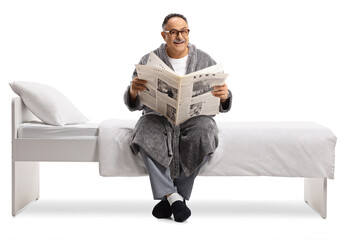 Poster - Mature man in  robe sitting on a bed and reading a newspaper