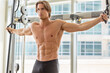 © PKpix - Topless male bodybuilder training in the gym with pull cable machine.