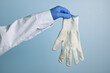 Doctor shows dirty white cotton glove. Medic hand with unhygienic protective fabric glove. Doctor hand wearing a blue nitrile glove holds another fabric. Blue gradient background.
