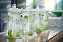 Glass pitchers with water with lime, cucumber and mint