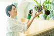 © One - 出勤前に観葉植物に水をやる女性