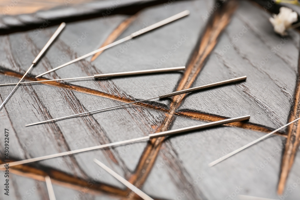 Acupuncture needles on wooden background, closeup