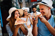 Happy traveling tourists friends having fun, eating pizza on summer vacation
