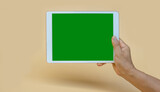 Fototapeta  - IPad handle the green screen with shadow below, light yellow background.