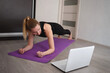 © Aleksandra Iarosh - young woman doing asana at home on yoga mat in front of laptop