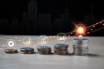 Gold and silver coins are flexible five stacks. There is a financial icon on them. On the right, there's a bright light bulb on it, line blue and yellow, orange and red, with a fuzzy background.