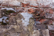 Fragment Of An Old Brick Wall With Dry Grass And Remnants Of Snow, Spring