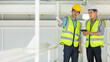© Bangkok Click Studio - Two engineers in yellow reflective vest and wearing safety hardhat working together in consruction site