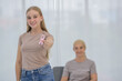© Bangkok Click Studio - A young and beautiful daughter holding and showing pink ribbon breast cancer symbol to encourage her mother's cancer patient and fortifies her to fight during the chemotherapy