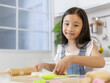 © Bangkok Click Studio - Cute little Asian girl using rolling pin during learing how to make bread and bakery in modern kitchen