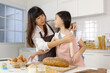 © Bangkok Click Studio - A cute and beautiful mother tie apron for her young and little daughter during she teaches her how-to cooking. Idea for love and relationship