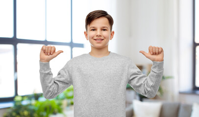 Wall Mural - childhood, fashion and people concept - happy smiling boy pointing fingers at himself over home room background