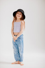 cute little girl plays with a black hat. the child tries on mothers clothes.