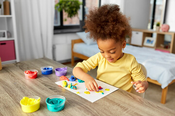 Wall Mural - childhood, creativity and hobby concept - little african american girl with modeling clay playing at home