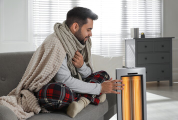 Sticker - Young man getting warm near electric heater at home