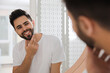 © New Africa - Handsome young man after shaving near mirror in bathroom